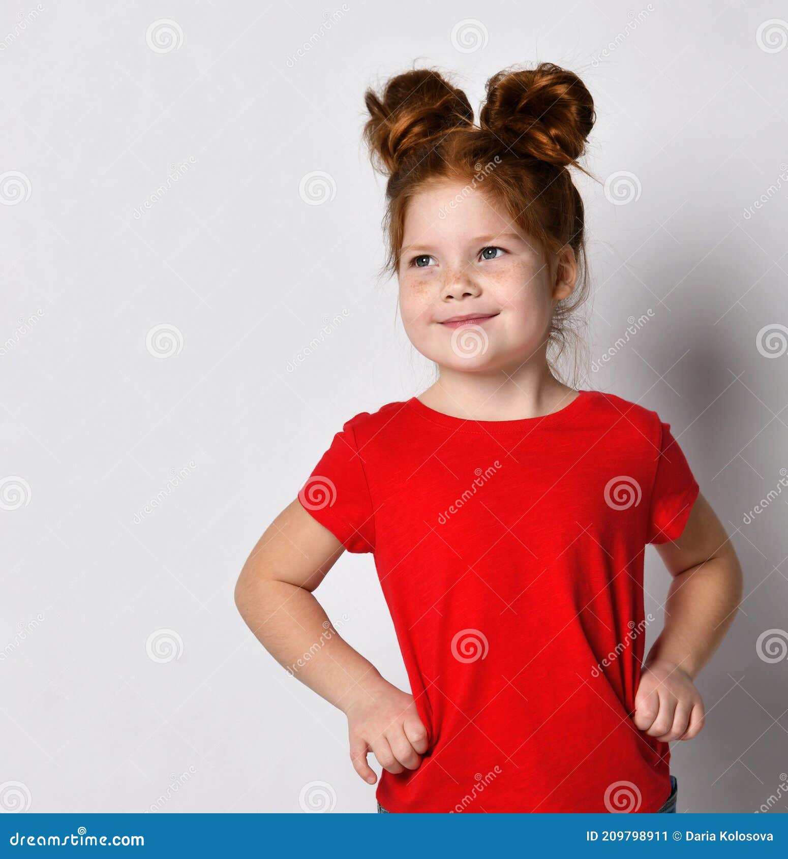 Una niña con una camiseta roja sostiene su cabello en sus manos