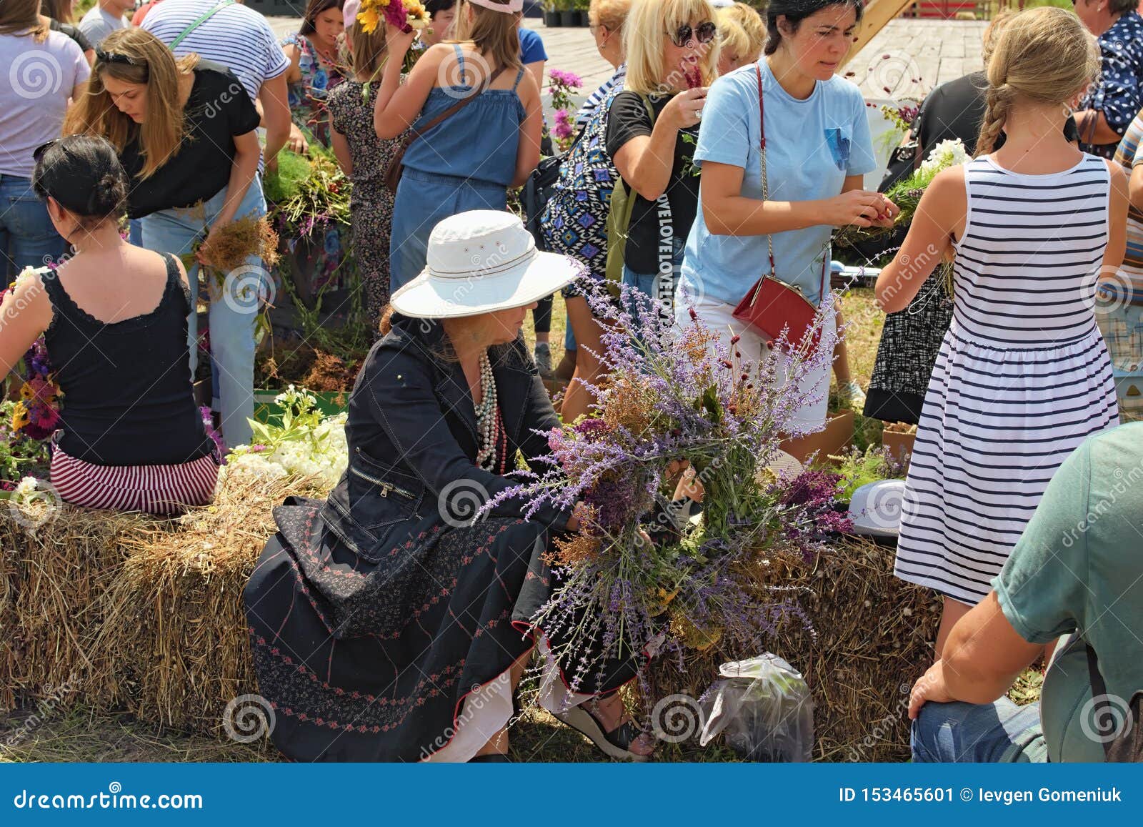 Kostivtsi, Ucraina 13 luglio 2019: La signora ha finito appena di fare la sua corona La gente sta tessendo le corone dai fiori selvaggi Concetto di estate Tradizione ucraina meravigliosa Berry Festival Brusviana