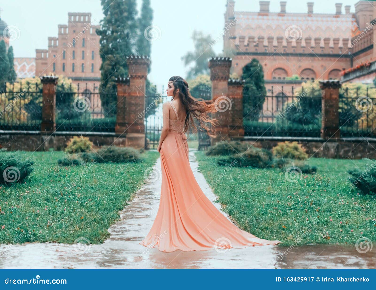 Una mujer con un traje medieval se para bajo la lluvia.