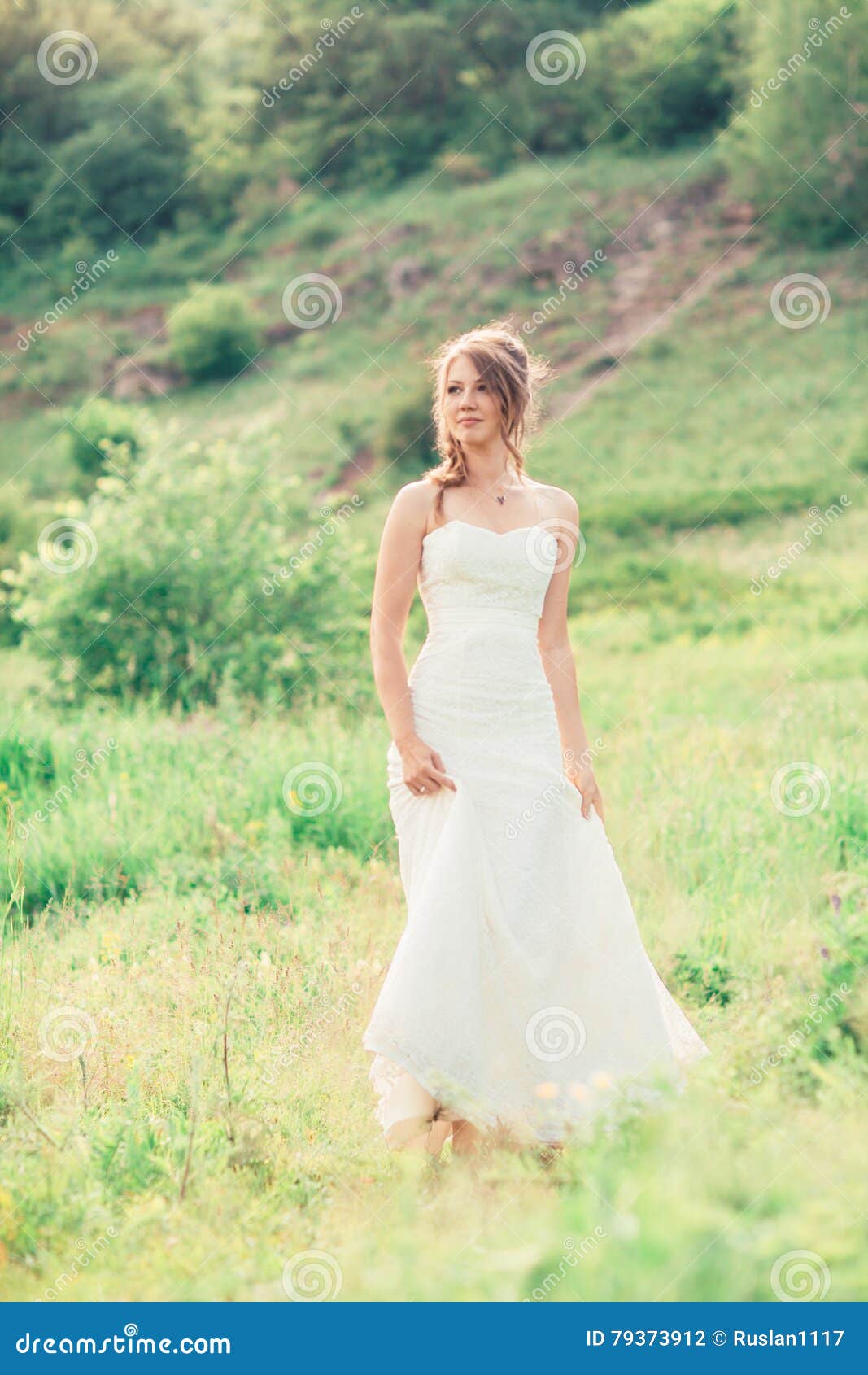 La sposa sta su un fondo di erba e delle montagne
