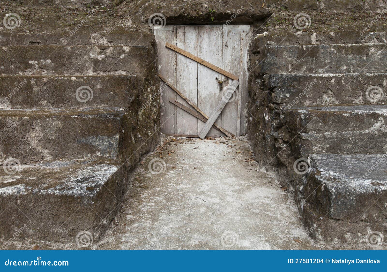 La trappe en bois est fermée, des escaliers autour