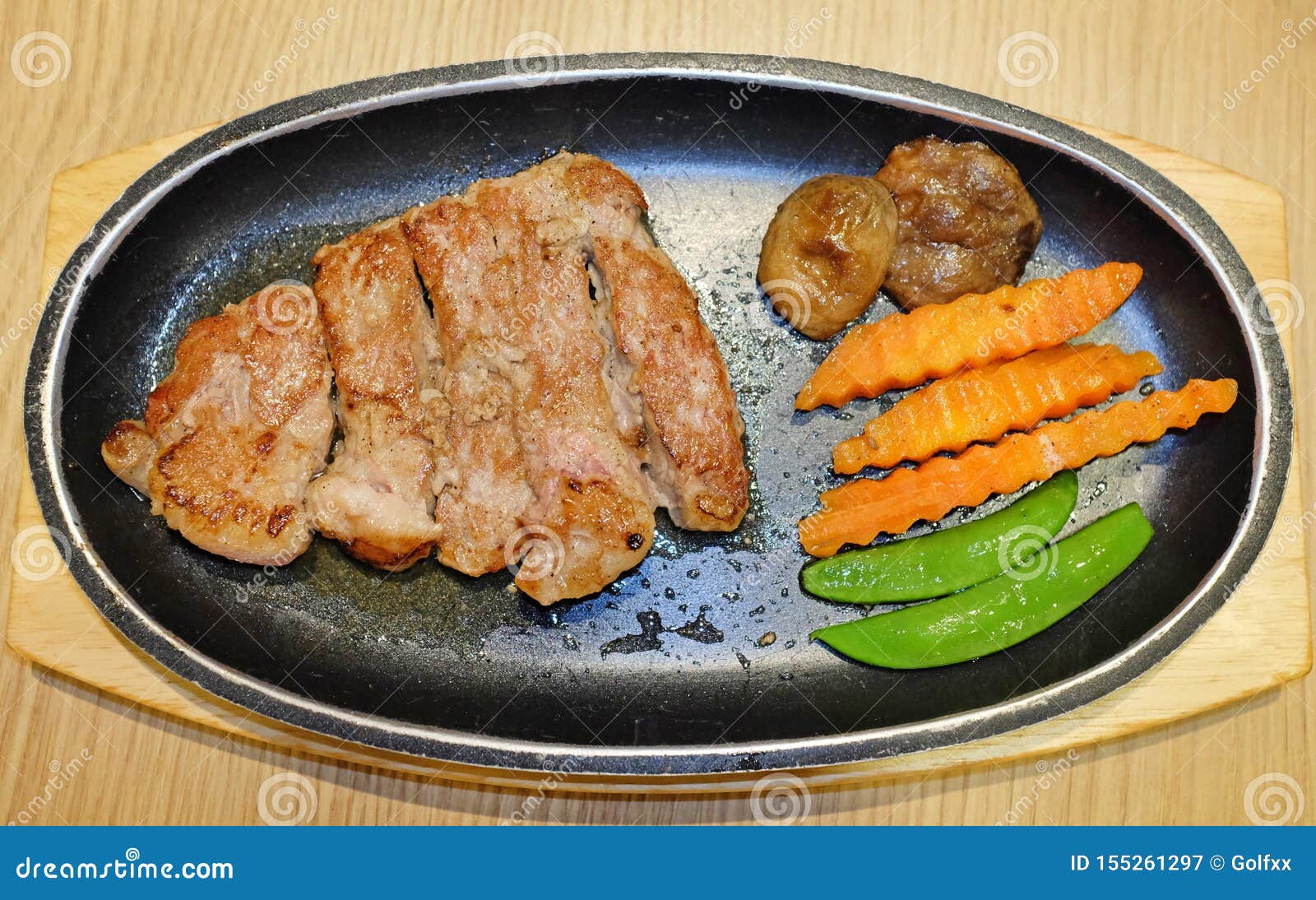 La vista superior de los filetes de carne de vaca asados a la parrilla sirvió con las verduras en el tablero de madera