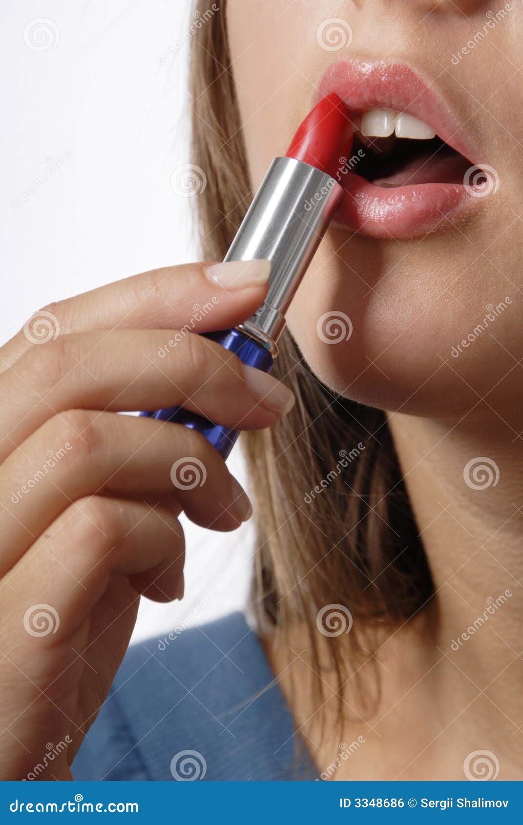 Labios rojos. Parte de la cara. La muchacha es labios de la pintura con el lápiz labial rojo en el fondo blanco. Se abre la boca.