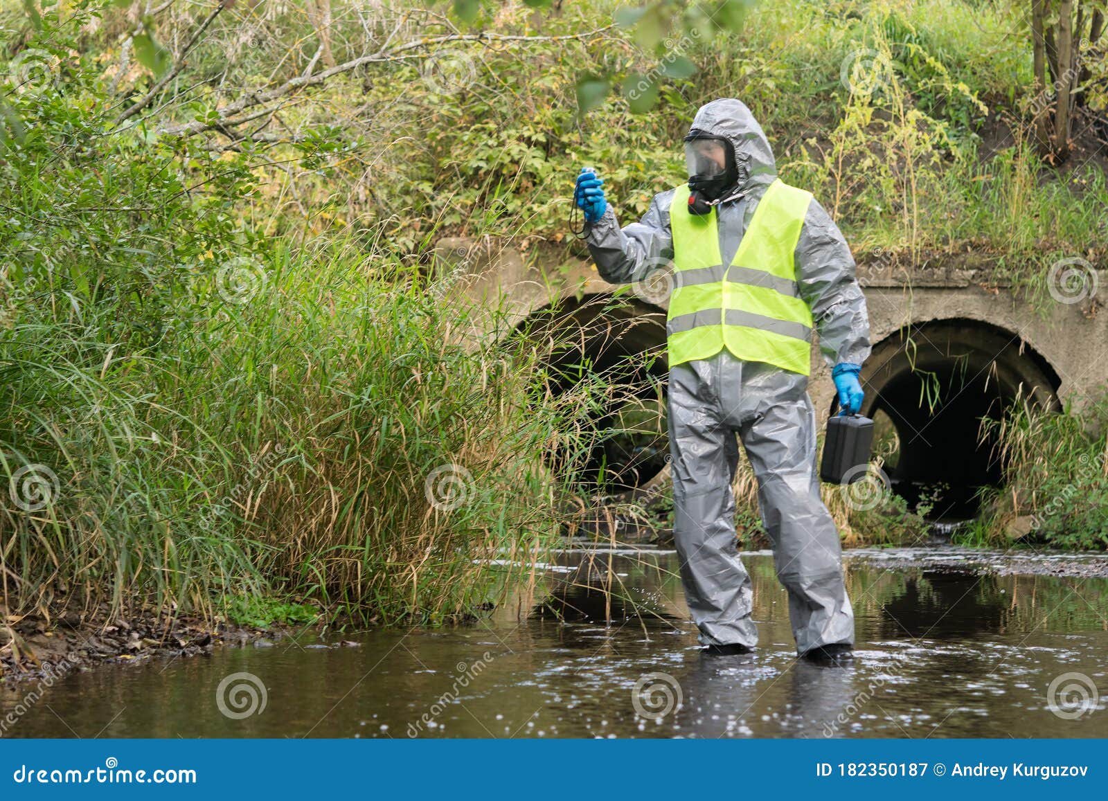 laboratory assistant in a special protective suit in the open air measures the level of environmental pollution with the device