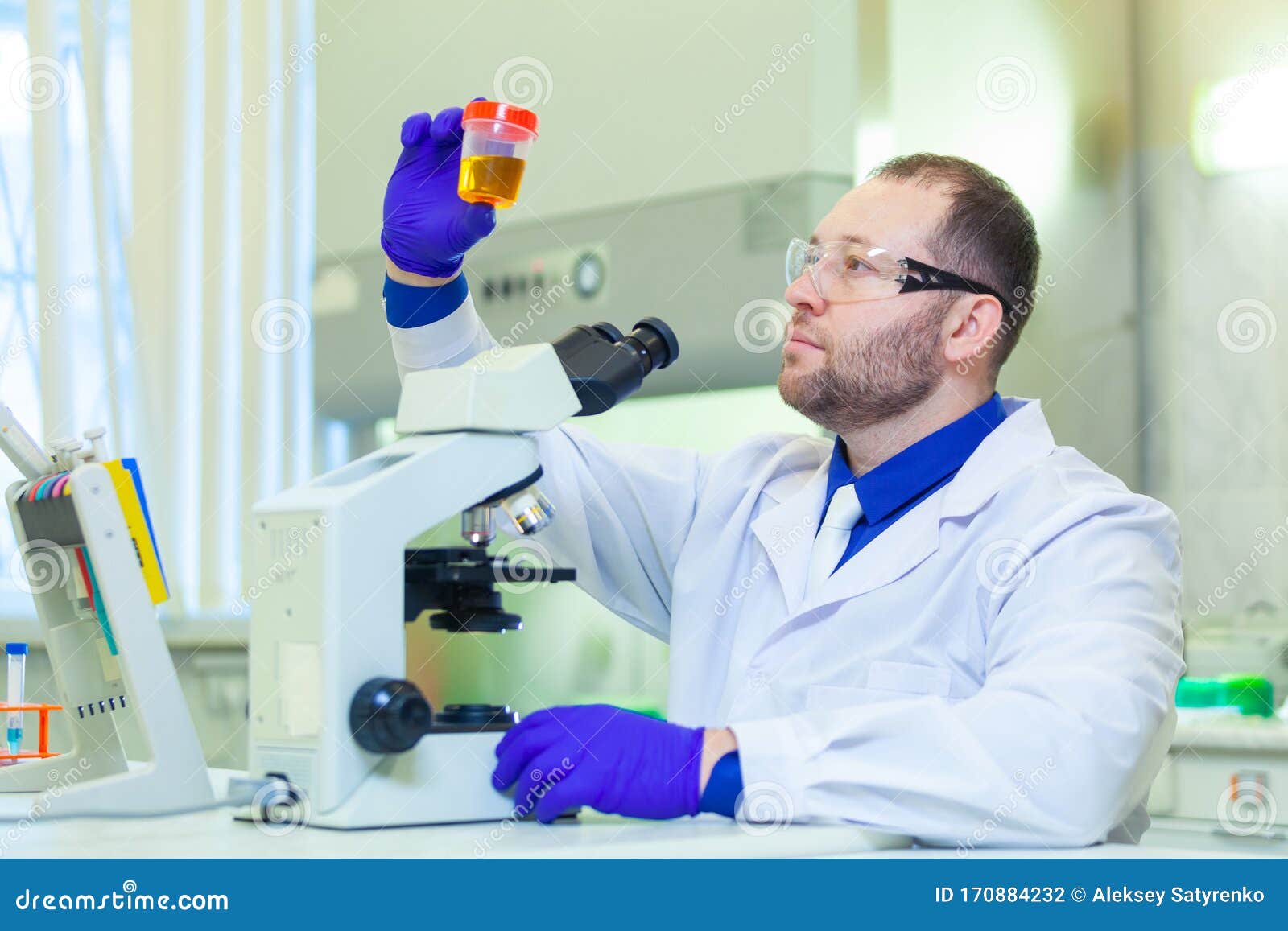 Laboratory Worker Performing Urinalysis Using Microscope and Laboratory