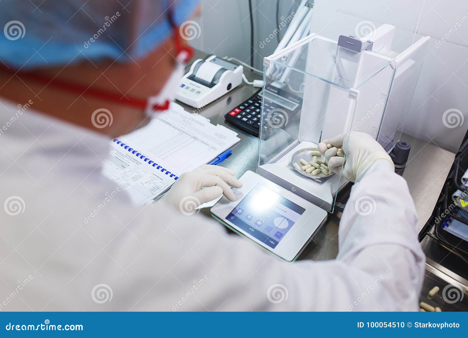 laboratory worker in sterile rubber gloves, weighs the manufactured tablets on the control scales.
