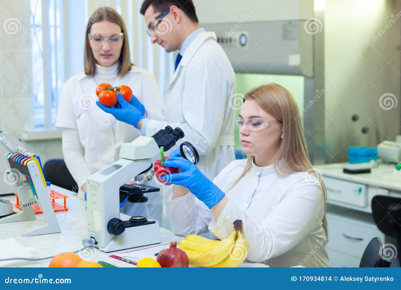 laboratory workers examining fruits and vegetables and making analysis for pesticides and nitrates.