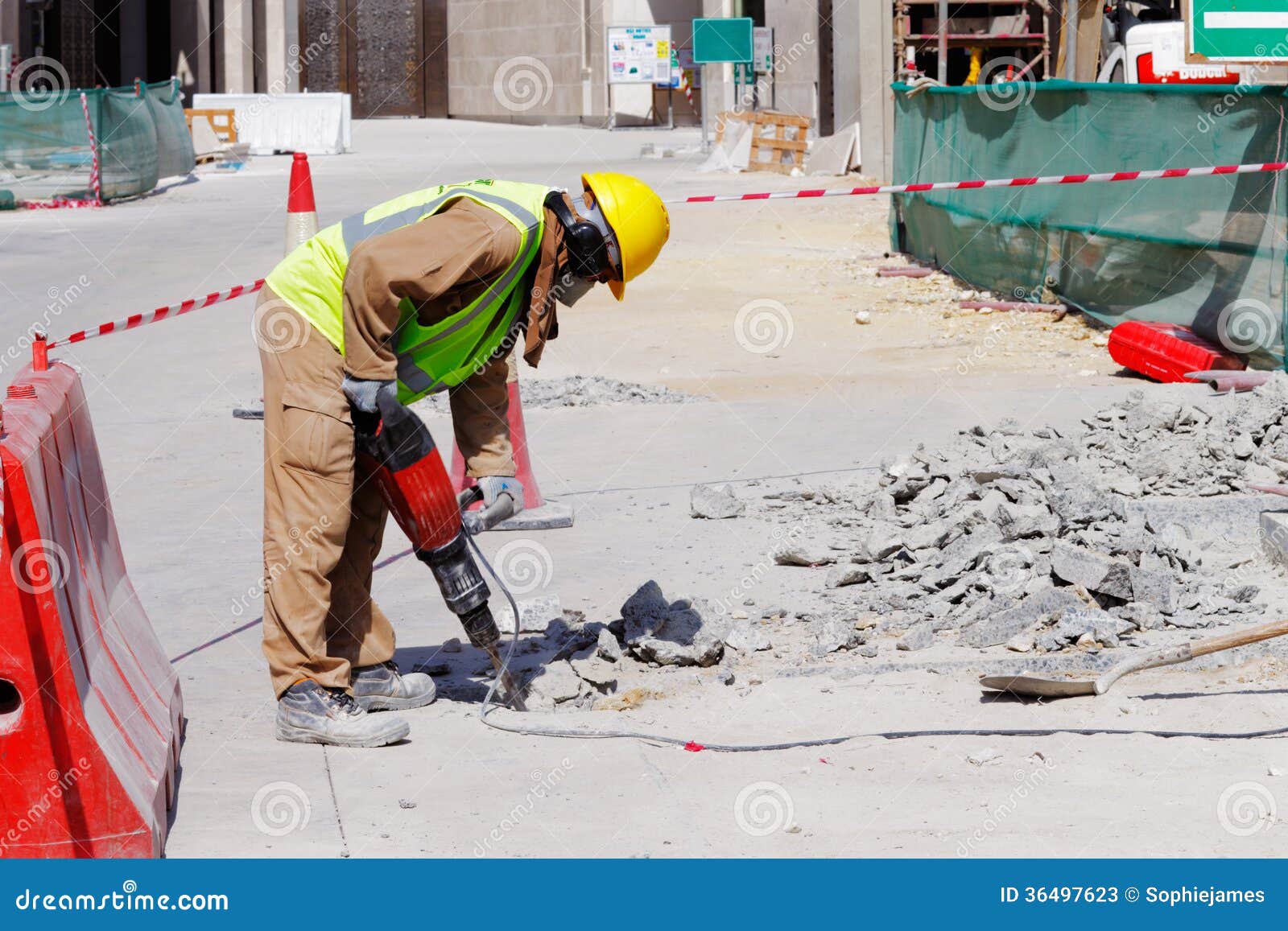 a laborer uses a jackhammer to break up a concrete pavement