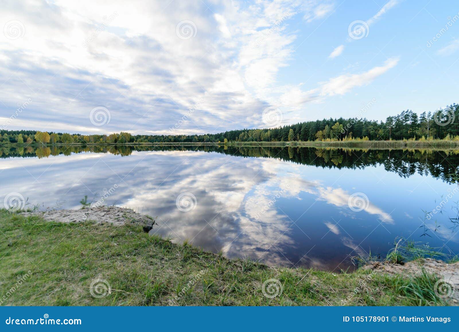 Lac avec des réflexions de l'eau dans le jour coloré d'automne avec les nuages blancs en ciel bleu