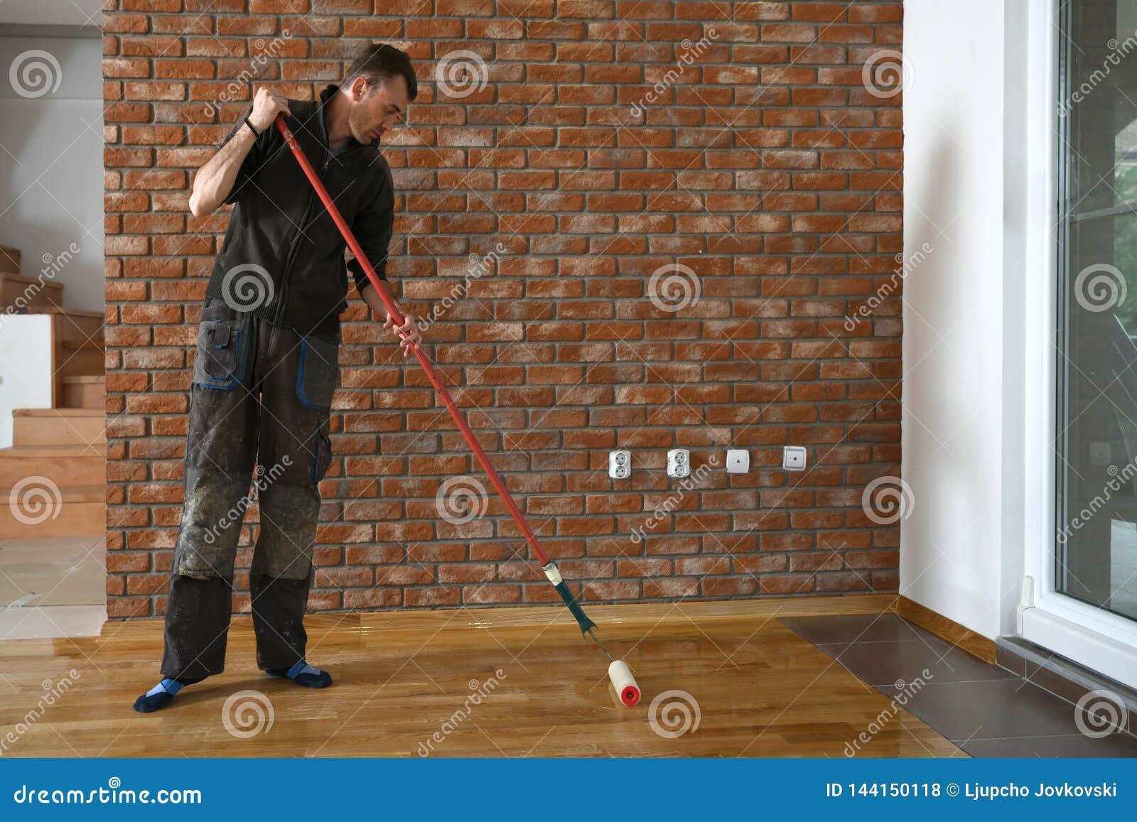 Lacquering Wood Floors Worker Uses A Roller To Coating Floors