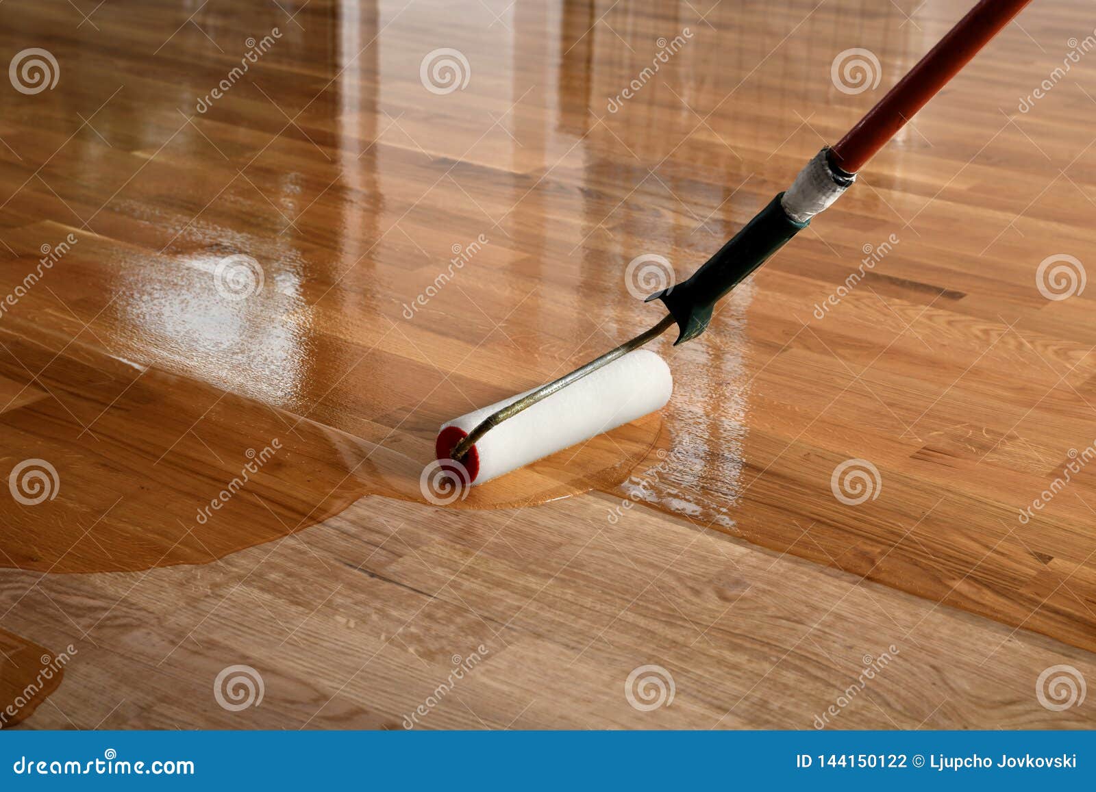 lacquering wood floors. worker uses a roller to coating floors