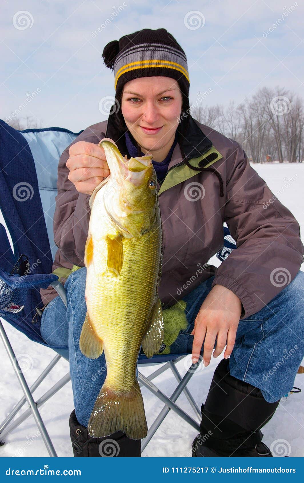 lady angler fisherwoman holds a large mouth bass caught ice fishing