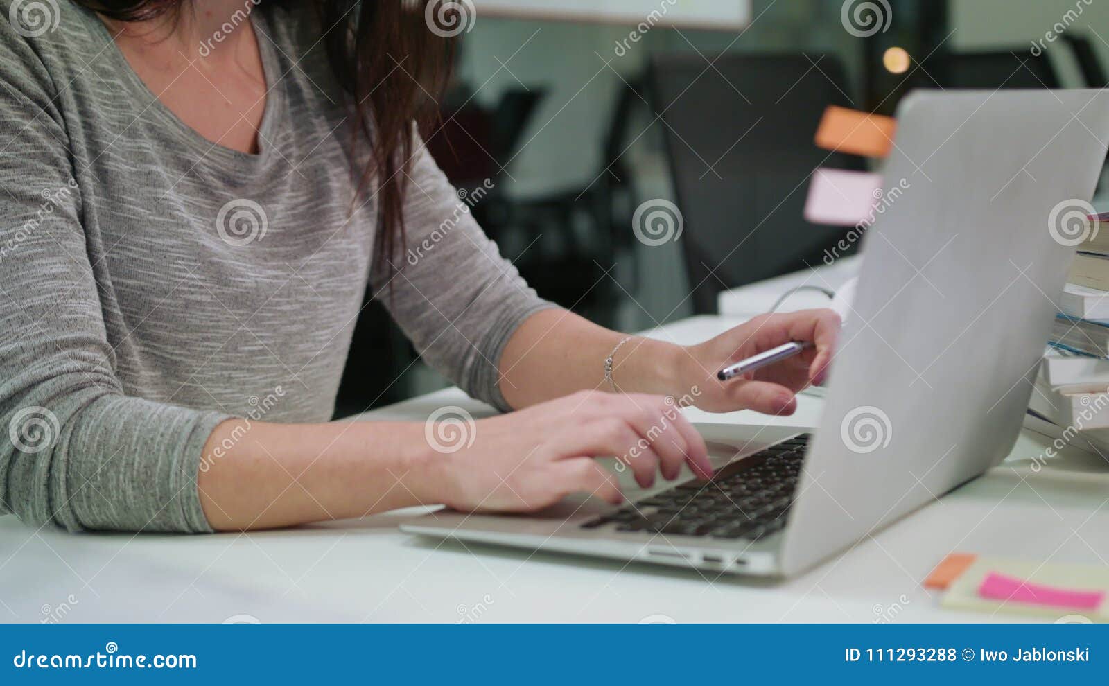 A Lady Sitting In The Office Typing On A Laptop Stock Photo