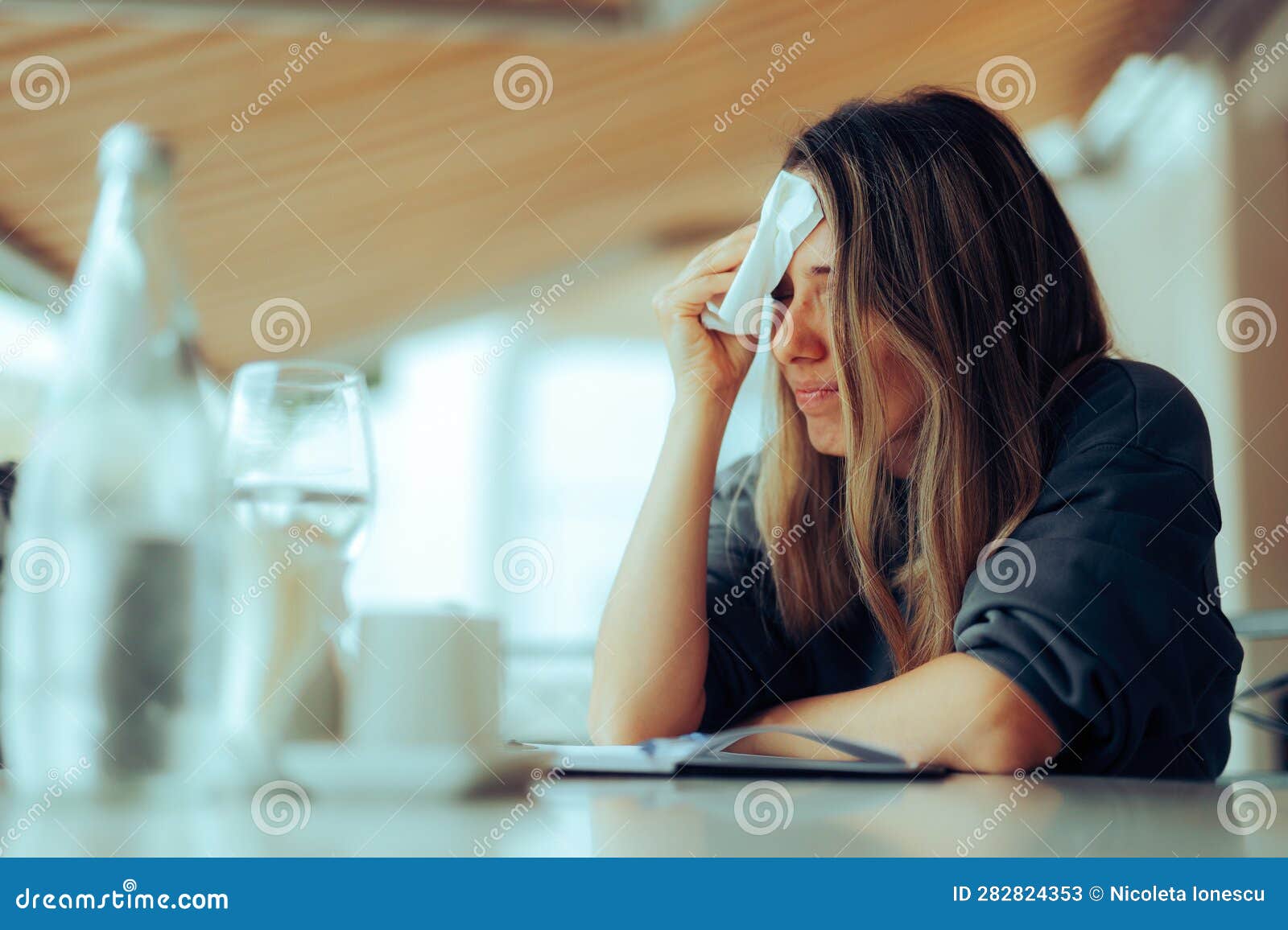 woman wiping sweaty forehead using a napkin