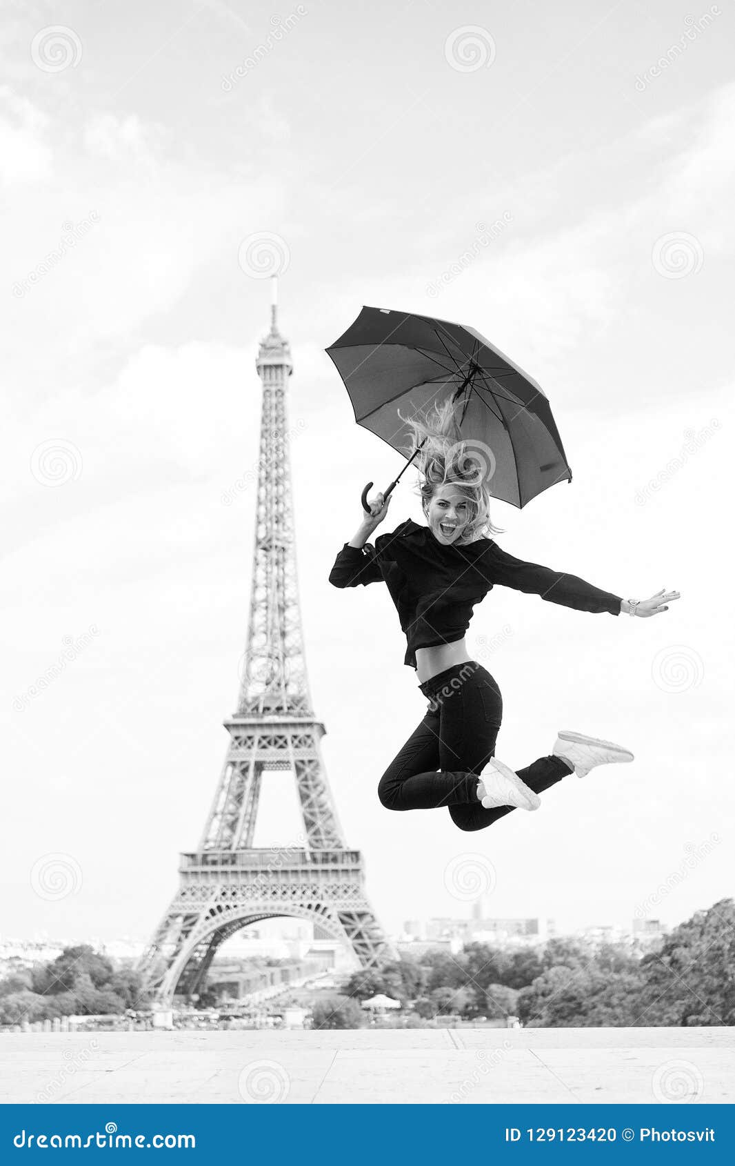 Lady with umbrella excited about visiting Eiffel Tower, sky background. Lady tourist sporty and active in Paris city center jumps up. Girl tourist enjoy walk and sightseeing. Dreams come true concept.