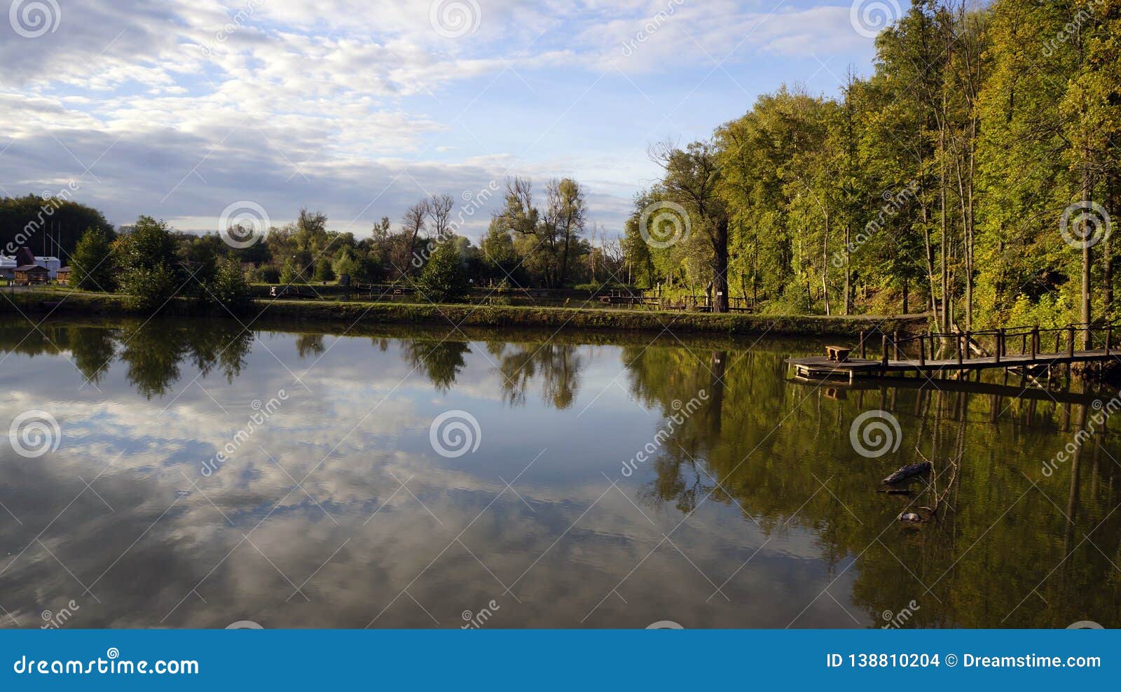 Lago no céu azul da lagoa da floresta. Céu azul com nuvens brancas que são refletidas no lago contra o contexto da floresta