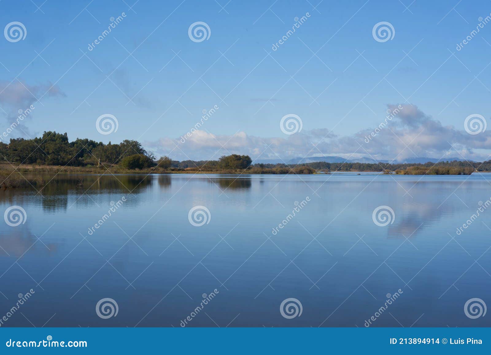 lake dam landscape with reflection of gardunha mountains and trees on a cloudy day in santa agueda marateca dam in portugal
