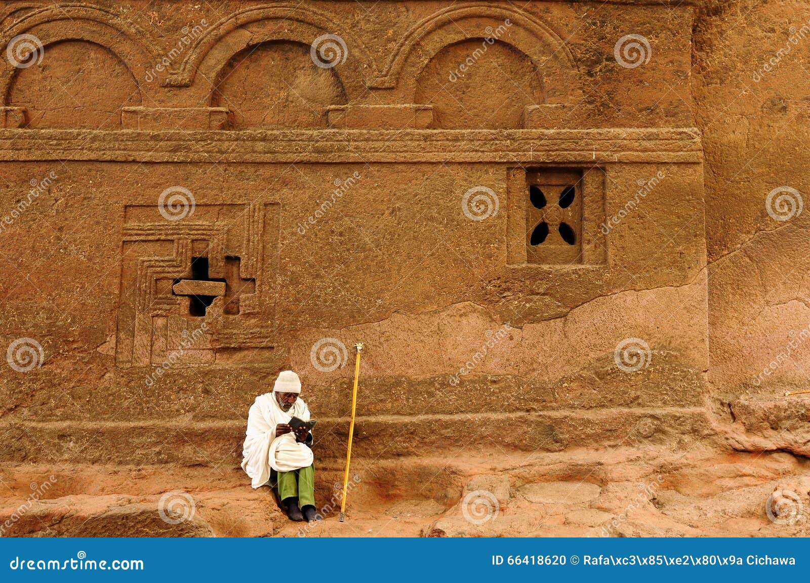 LALIBELA, ETIÓPIA - 30 DE AGOSTO: O peregrino etíope pela parede da igreja antiga cinzela na rocha contínua em Lalibela, Etiópia em Lalibela no 30 de agosto de 2013