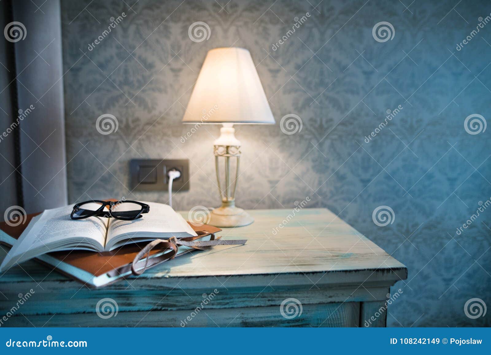 a lamp and a book on a bedside table in a hotel room.