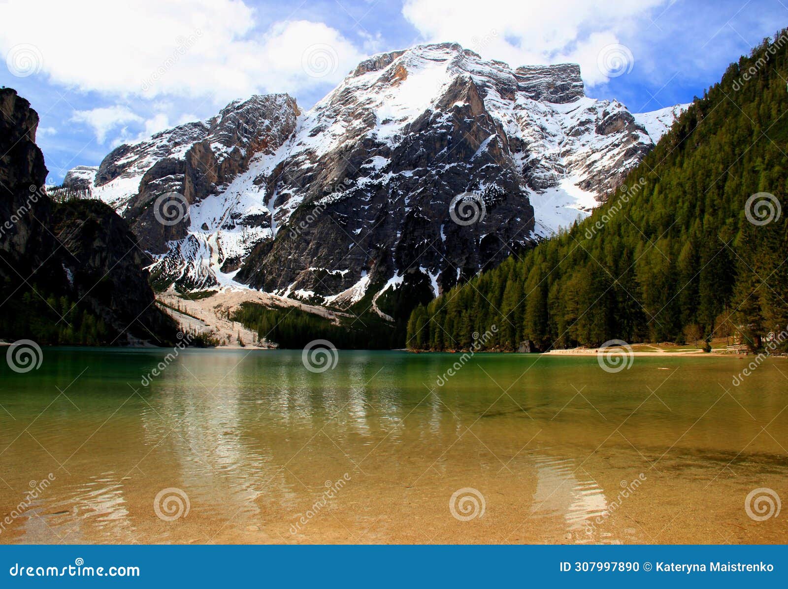 landscape with the emerald surface of lago di braies lake and snowcapped mountains in the dolomites, italy