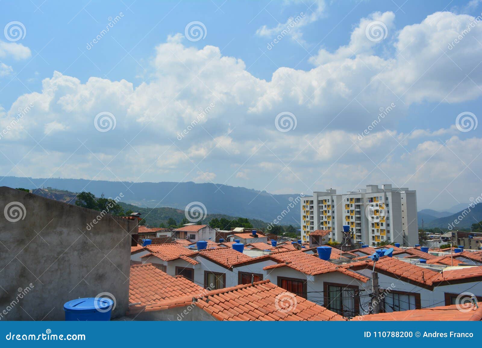 a landscape of some houses seen from the roof and a concrete wall with a blue sky in the background