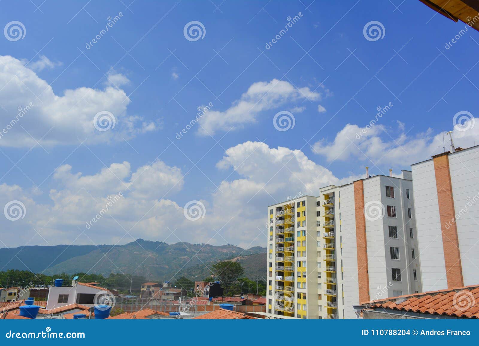 a landscape of some houses seen from the roof and yellow building wall with a blue sky in the background