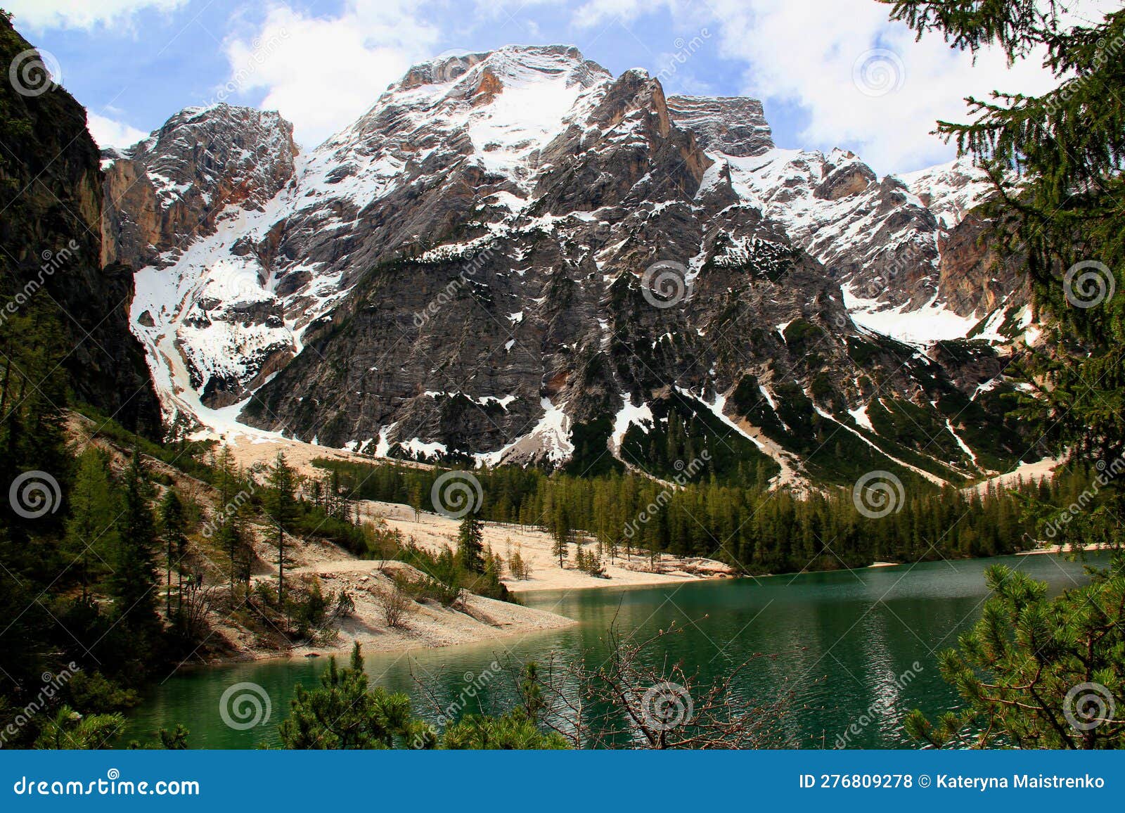 view of the emerald smooth surface of lago di braies lake and snow capped mountains in the dolomites