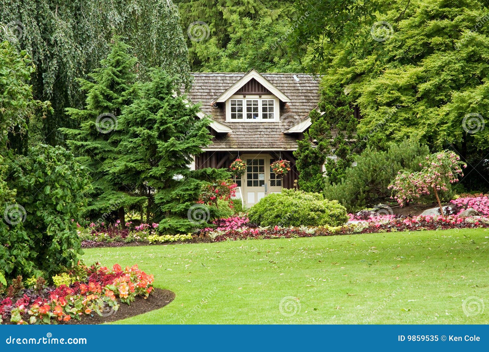  log cottage in the woods with colorful flower landscaping and gardens