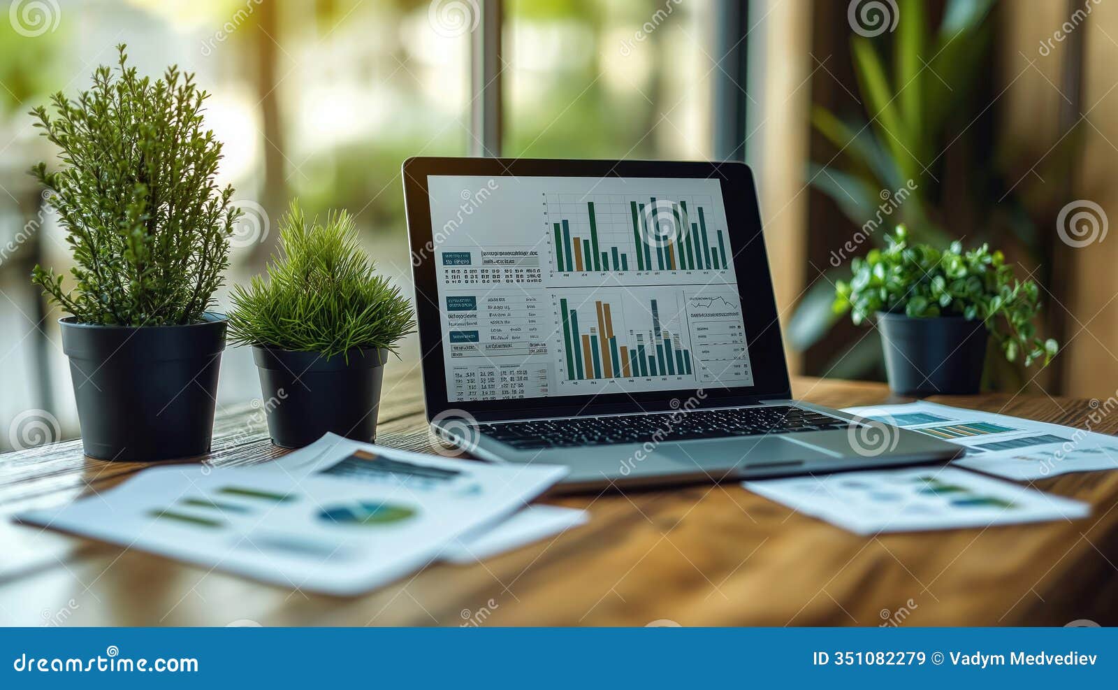 laptop screen displays financial graphs. printed quarterly reports placed alongside tablet. analysis of business growth shown.