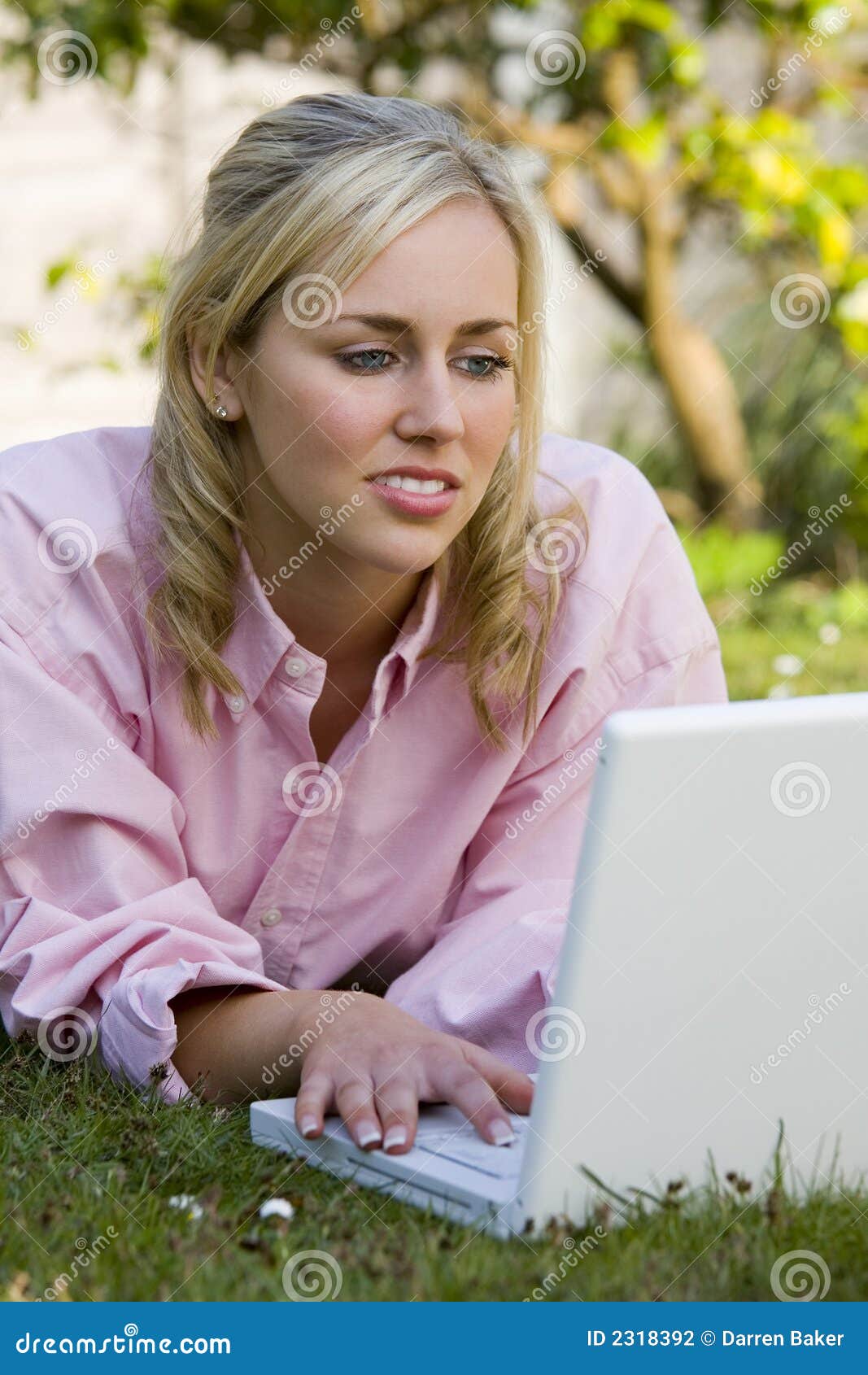 Laptop van de zomer. Een mooie jonge blonde vrouw die haar laptop met behulp van terwijl buiten het leggen op haar op het gras