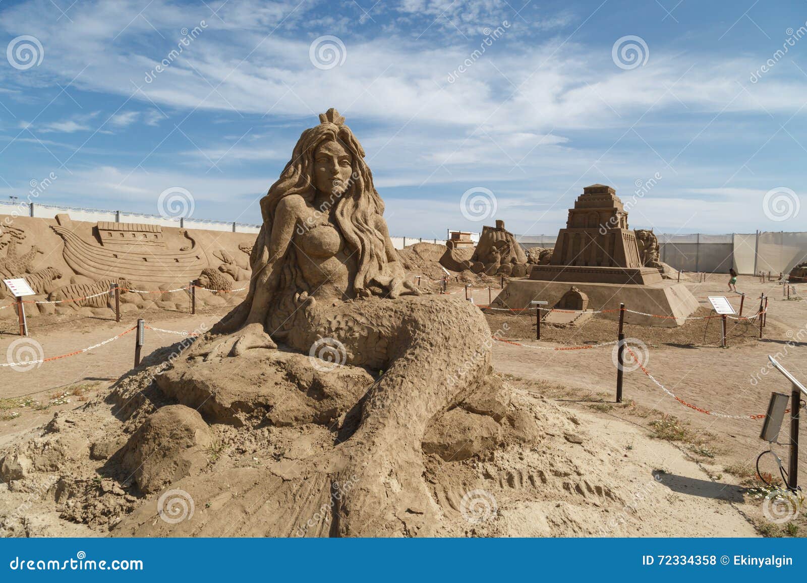 Lara Sandland Sculptures. ANTALYA, TURKEY - APRIL 23, 2016 : View of big sand sculpture of mythological characters made in Lara Beach, Antalya for sandland project, on cloudy blue sky background.