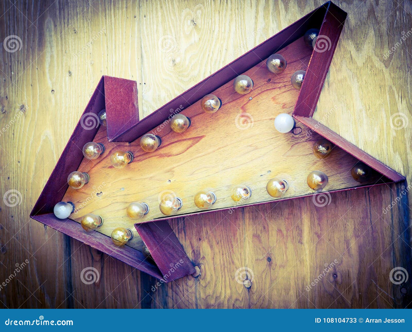 large antique arrow, rusty red on wooden ply.