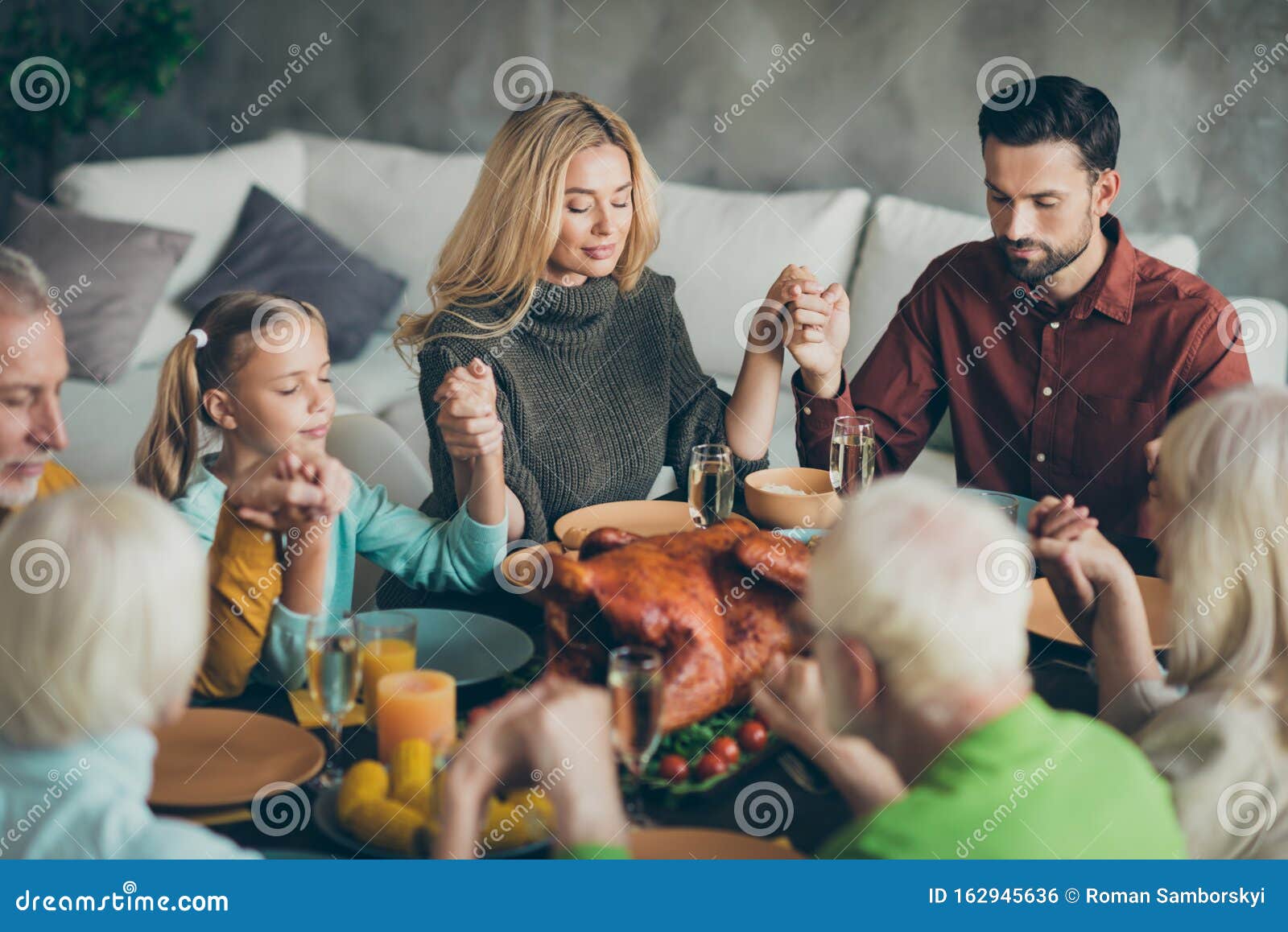 large family gathering on thanksgiving day sit table enjoy october meal hold hands pray meeting mature relatives small
