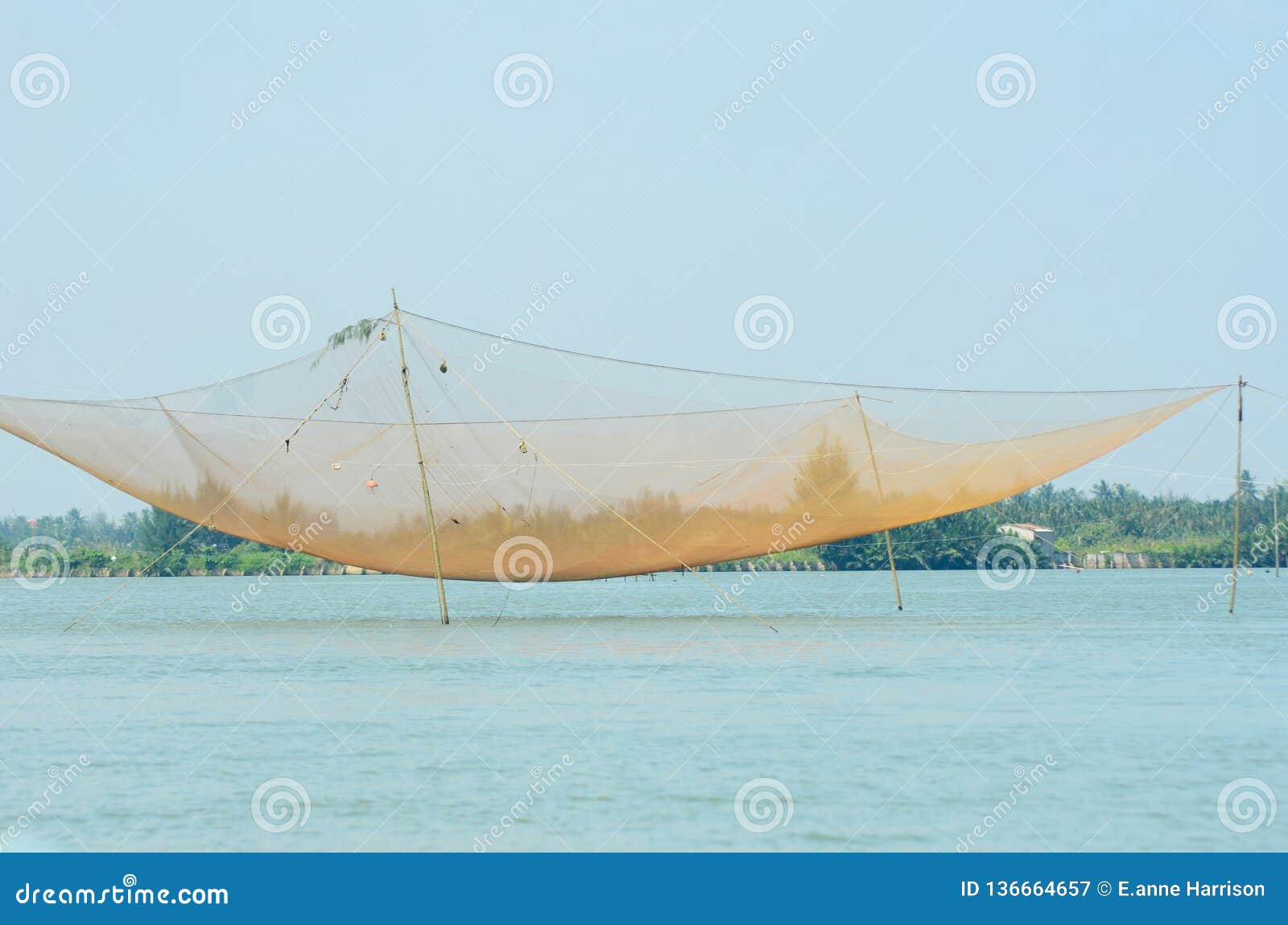 A Large Fishing Net Hanging Over Blue Water Stock Image - Image of