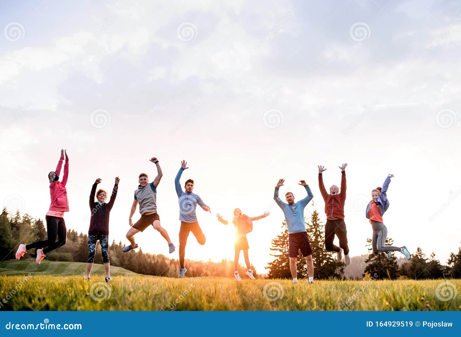 large group of fit and active people jumping after doing exercise in nature.