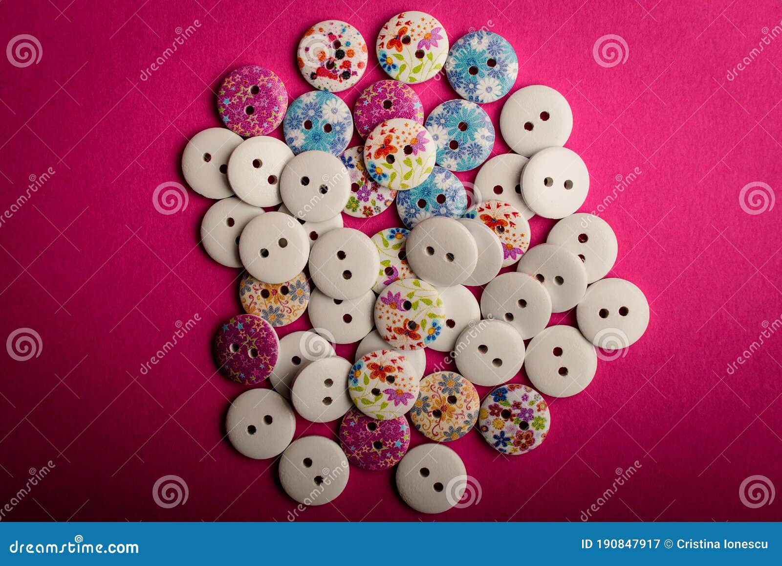 large group pf delicate light white and painted wooden buttons on dark pink texted cardboard background, displayed centered, top v