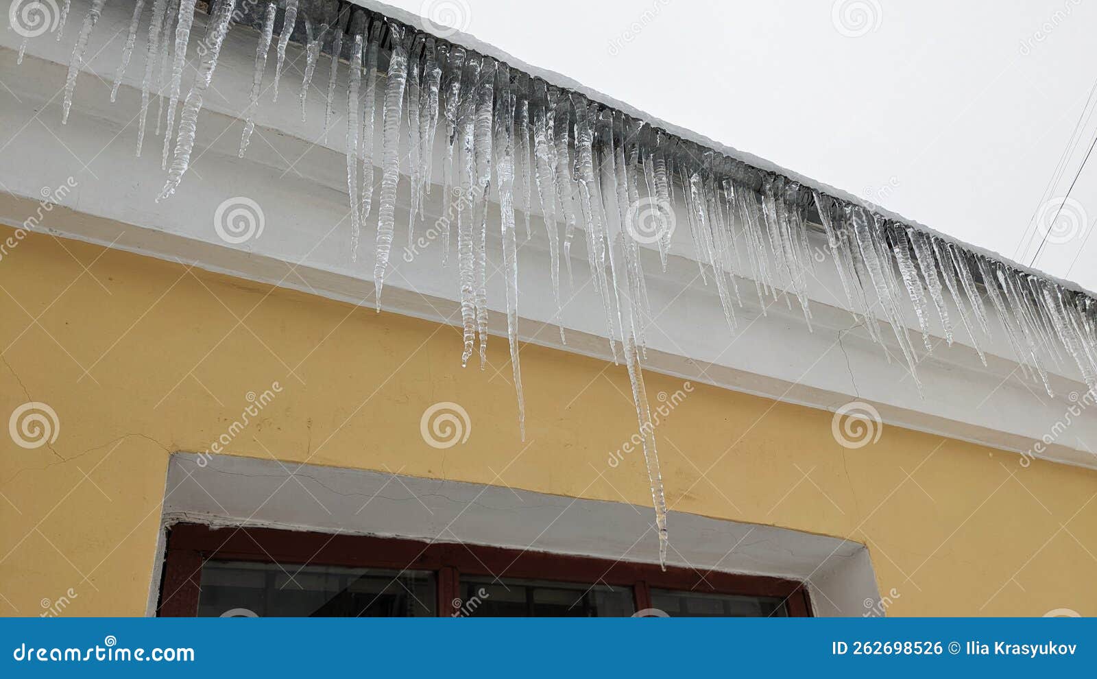 Large Icicles Hang from the Roof of the House. Danger of Falling Ice Icicles. Stock Photo