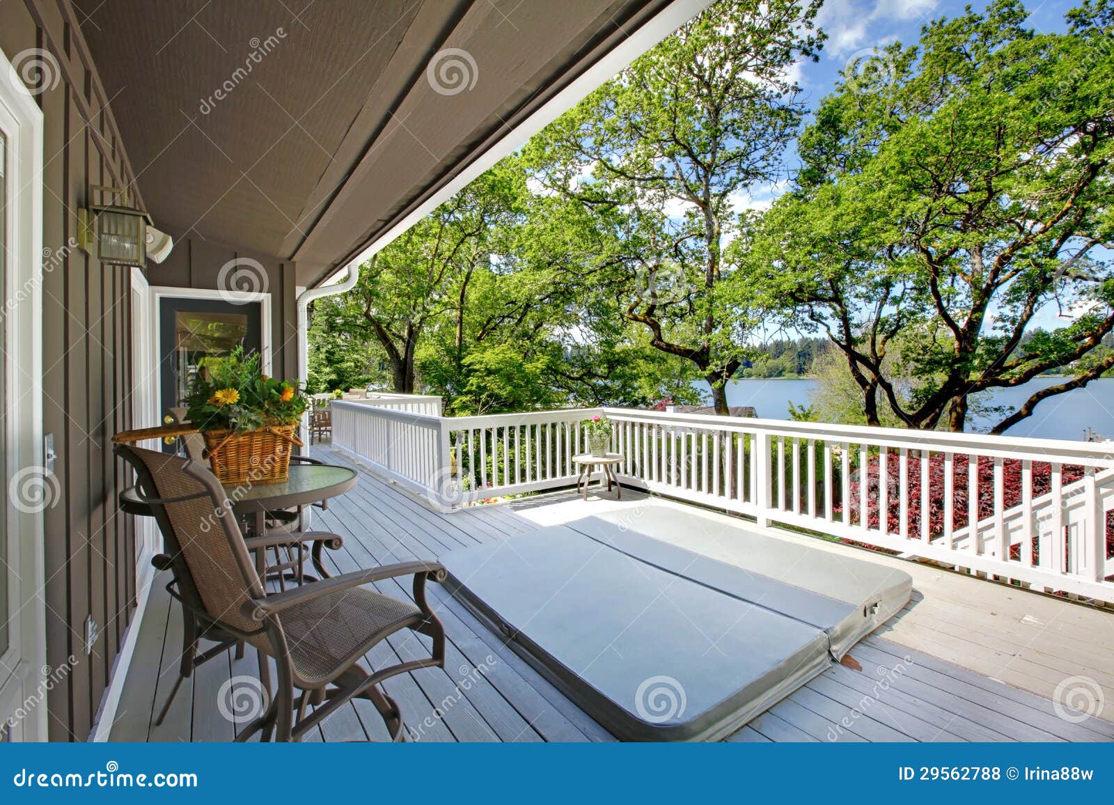 large long balcony home exterior with hot tub and chairs, lake view.