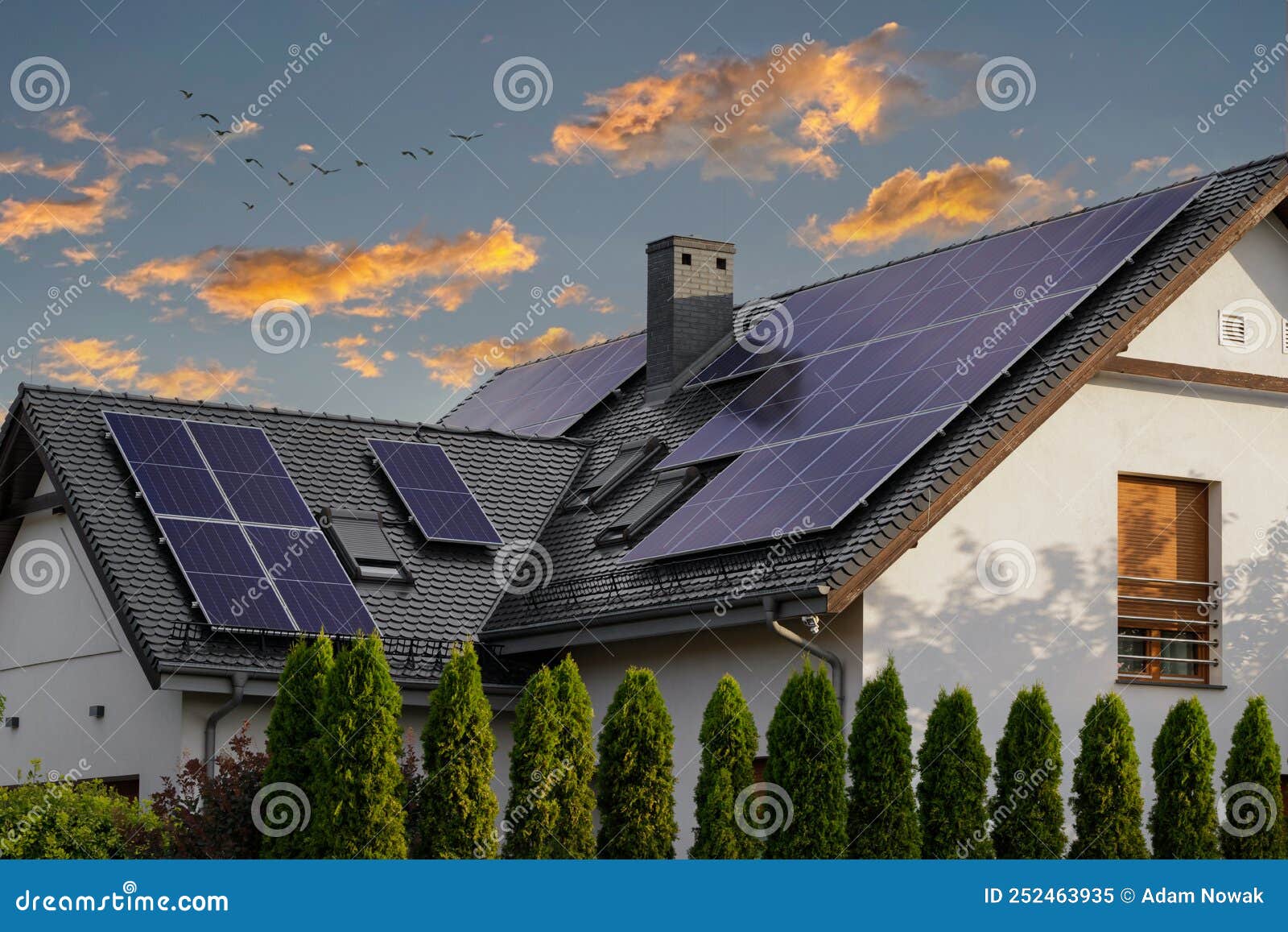 modern house with blue solar panels on the roof. end of the day, sunset. idyllic atmosphere