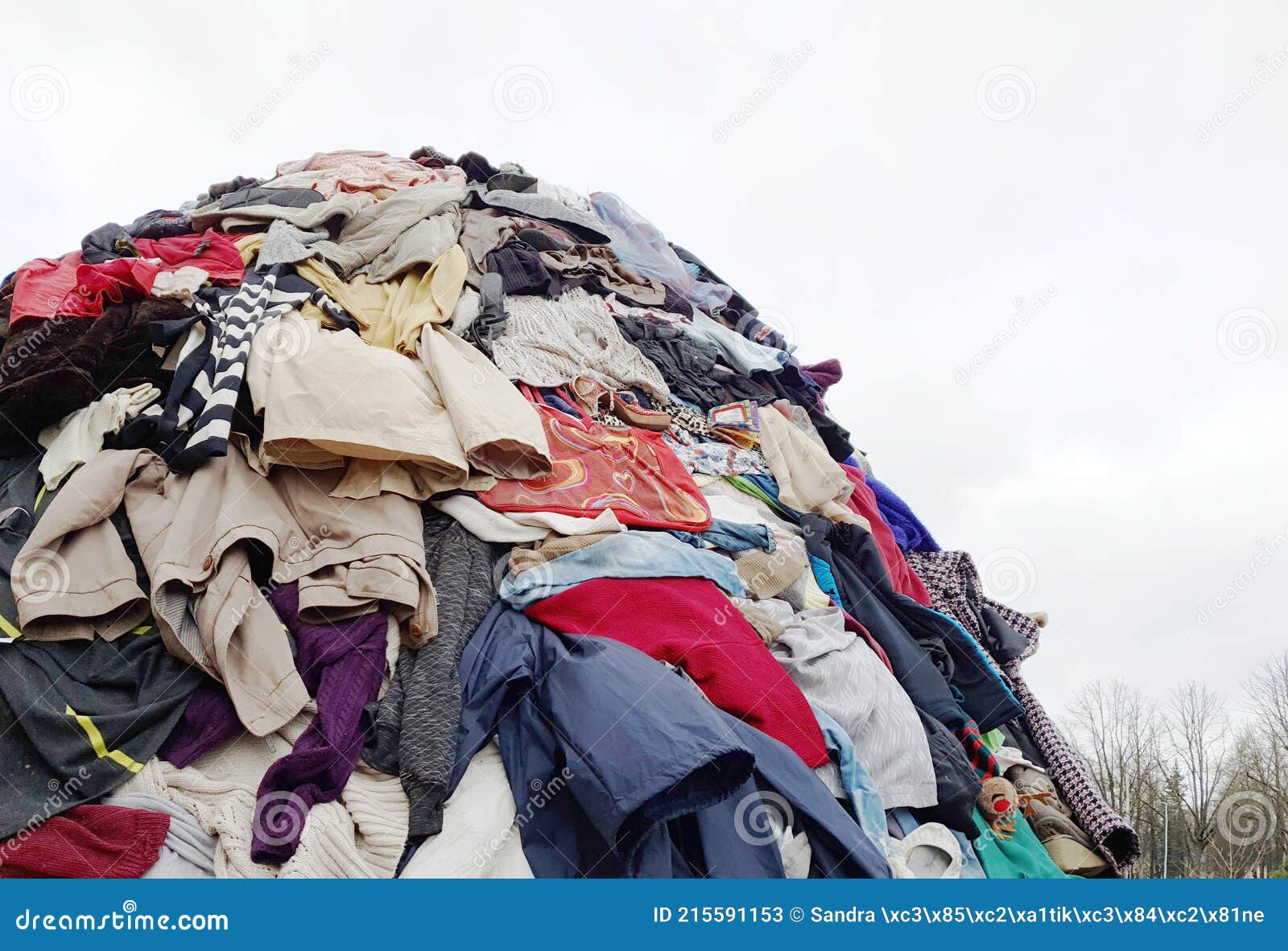 large pile stack of textile fabric clothes and shoes. concept of  fashion industry pollution, sustainability, reuse of garment.
