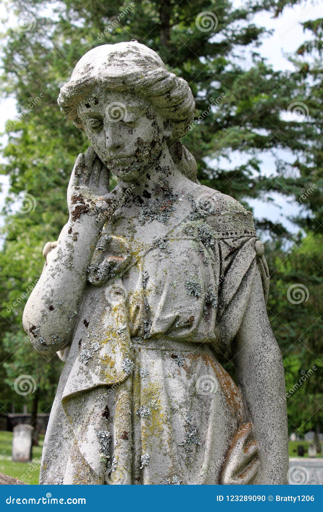 Large Stone Sculpture Of Weeping Angel Covered In Moss In Cemetery