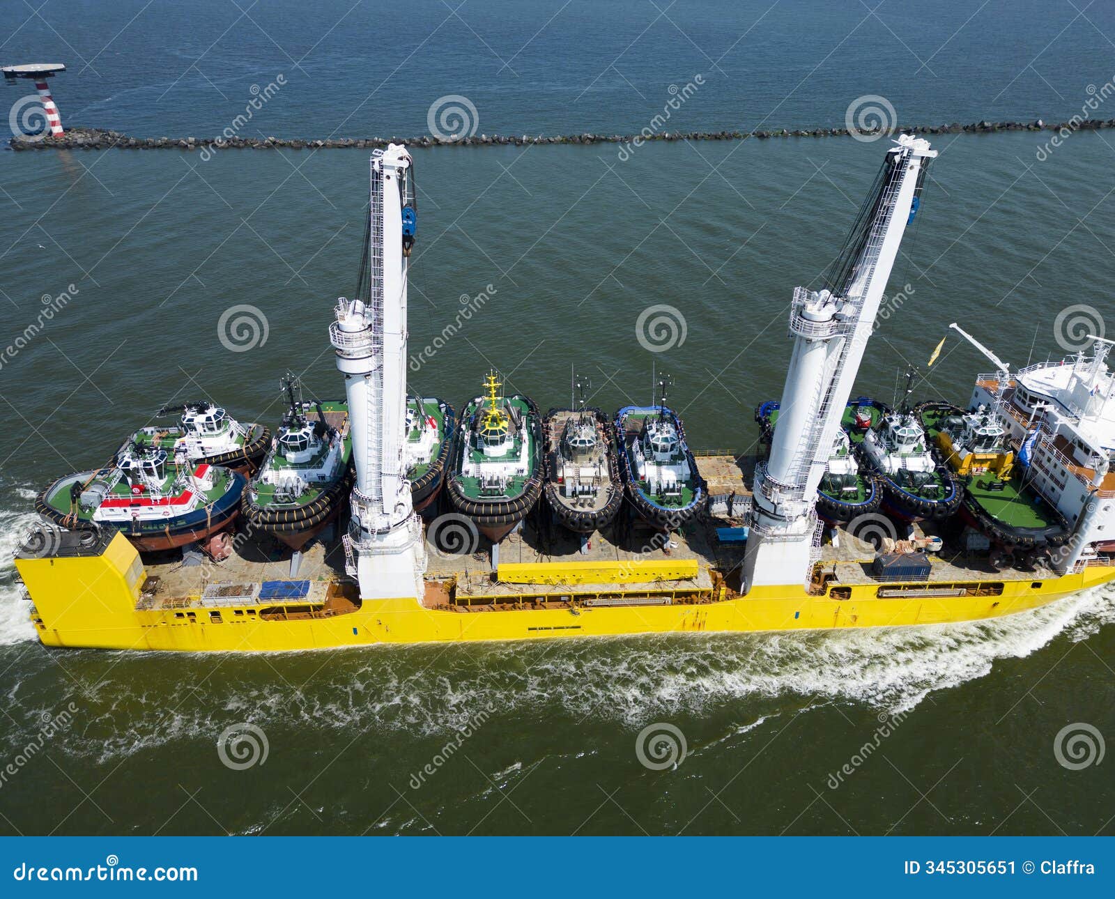 a large vessel with unique lifting capabilities carrying multiple tugboats