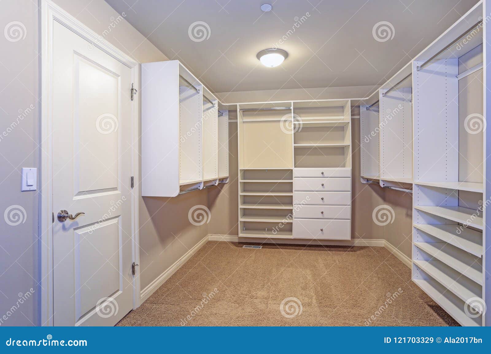 large walk-in closet with white shelves, drawers