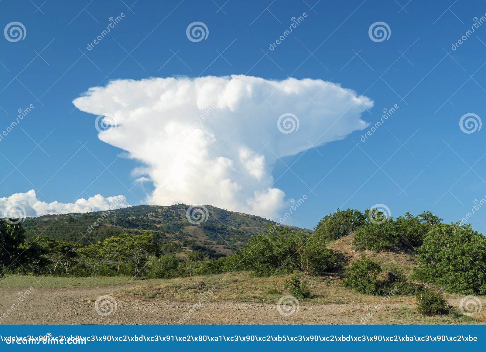 a large white cloud in the  of a mushroom over the mountains. crimea. choban-kule.
