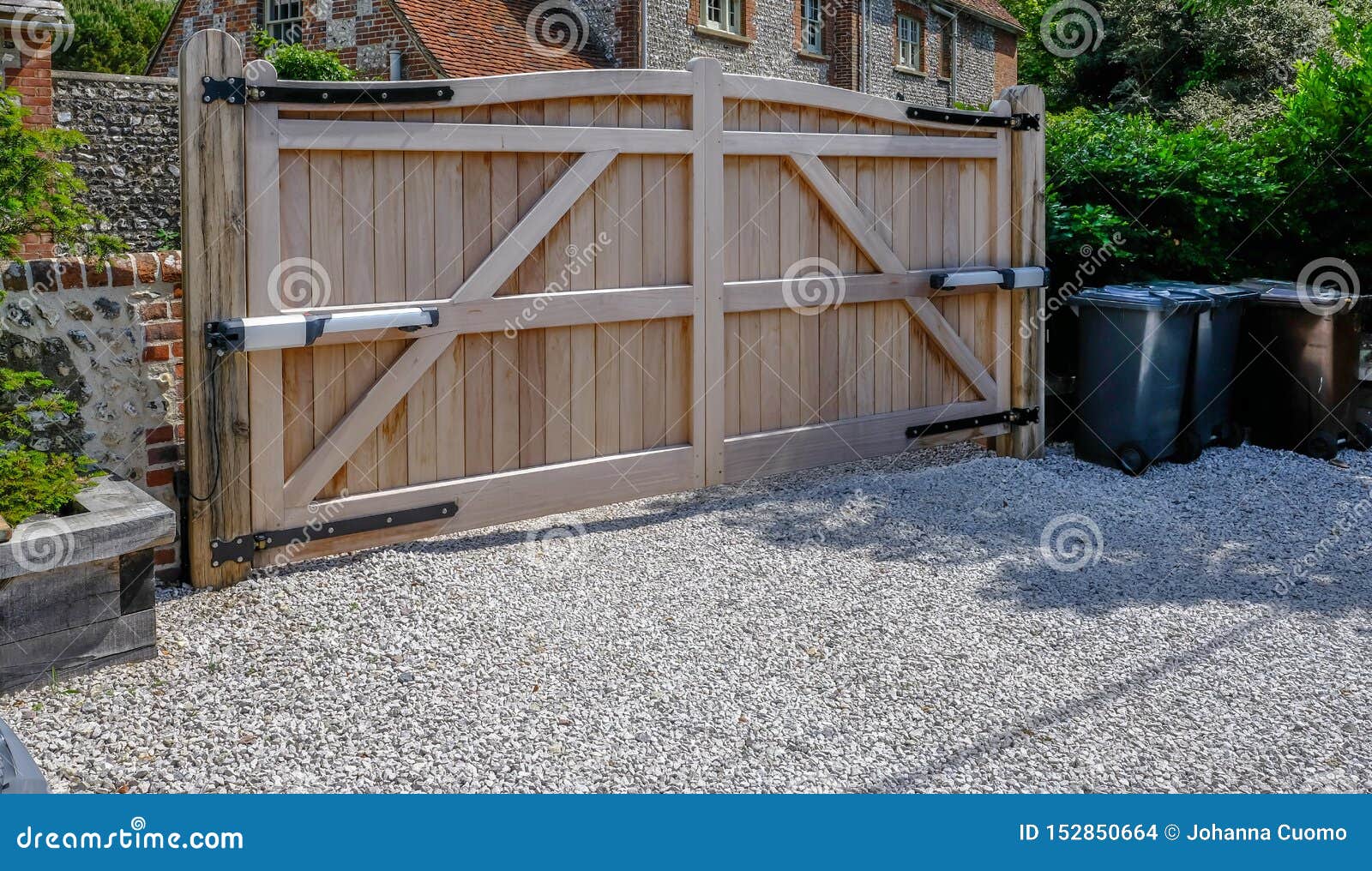 large wooden entry electric gates with stone driveway