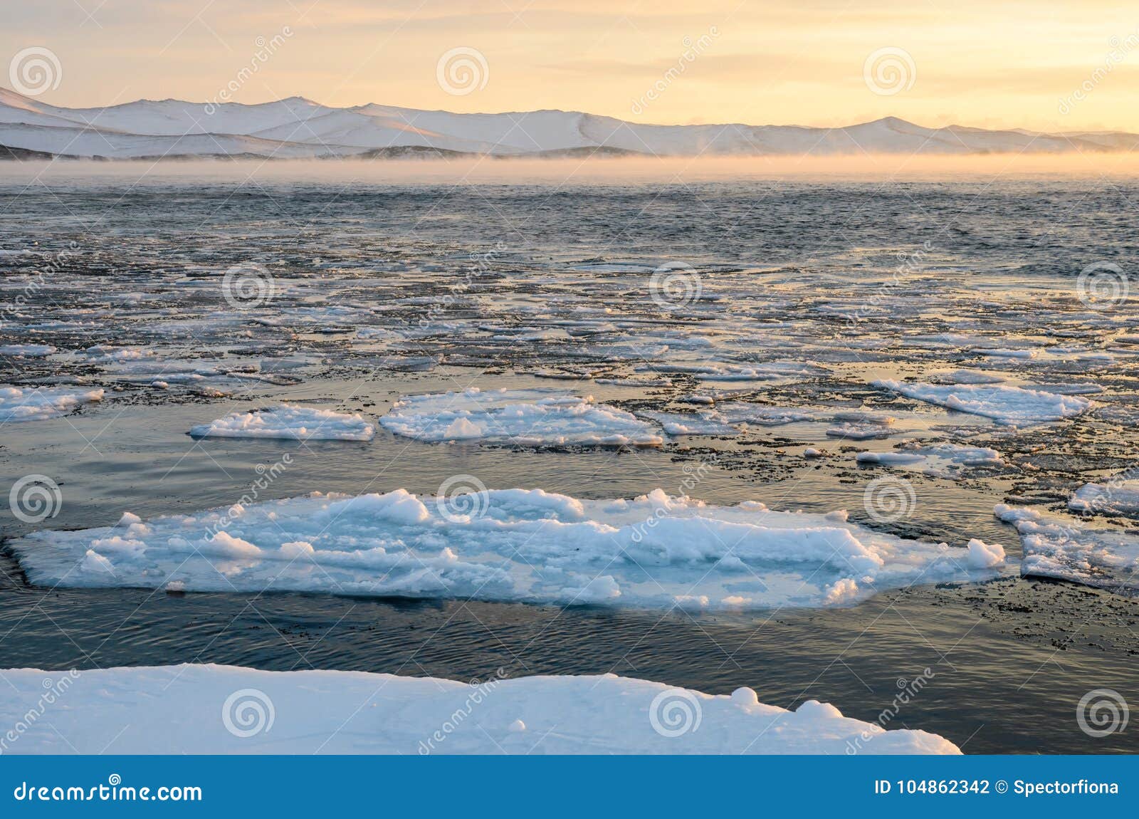 Las masas de hielo flotante de hielo que flotan en la niebla riegan en el lago Baikal, Rusia Puesta del sol