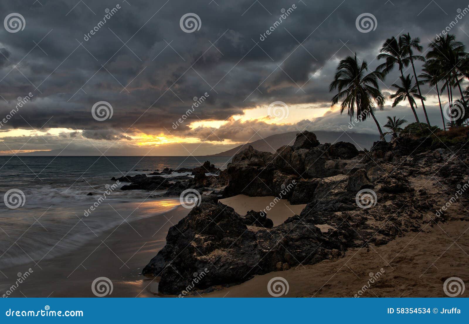 Las nubes de tormenta en la puesta del sol en la Hawaii varan. La puesta del sol empuja a través de las nubes de tormenta en Charlie Young Beach en la ciudad de Kihei en la isla de Maui, Hawaii