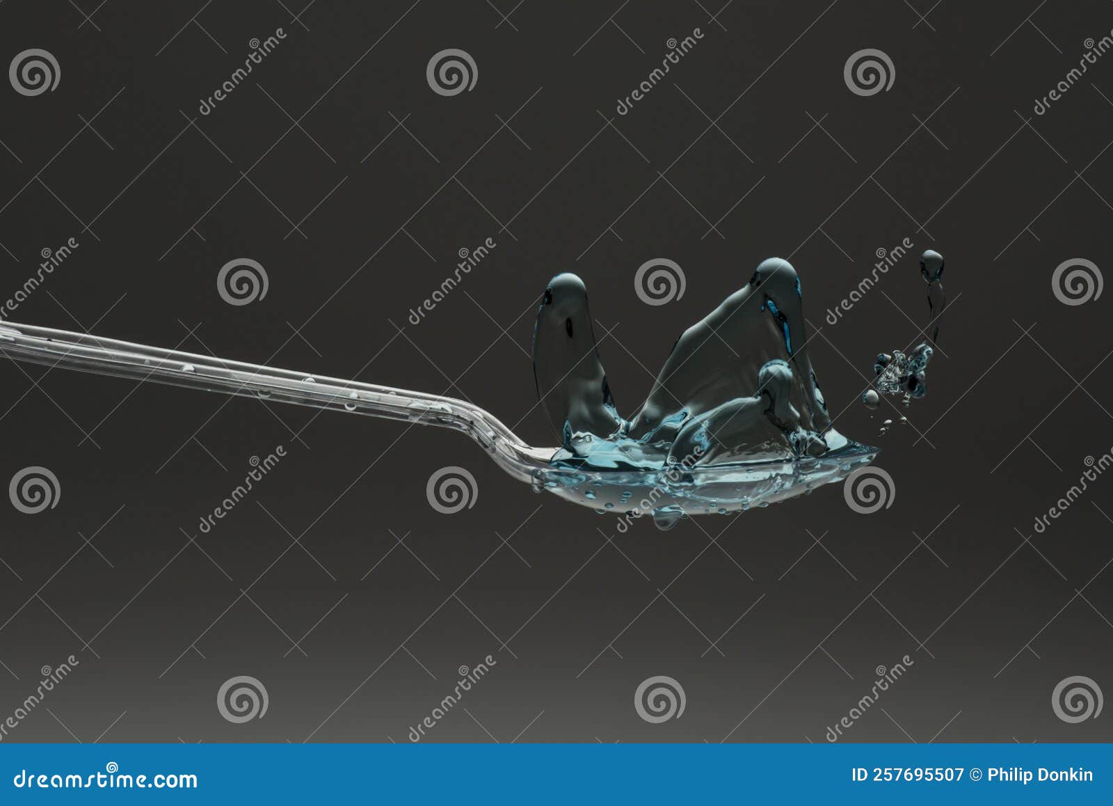 lastic spoon with water drops frozen at high speed showing surface tension and droplet splash structure