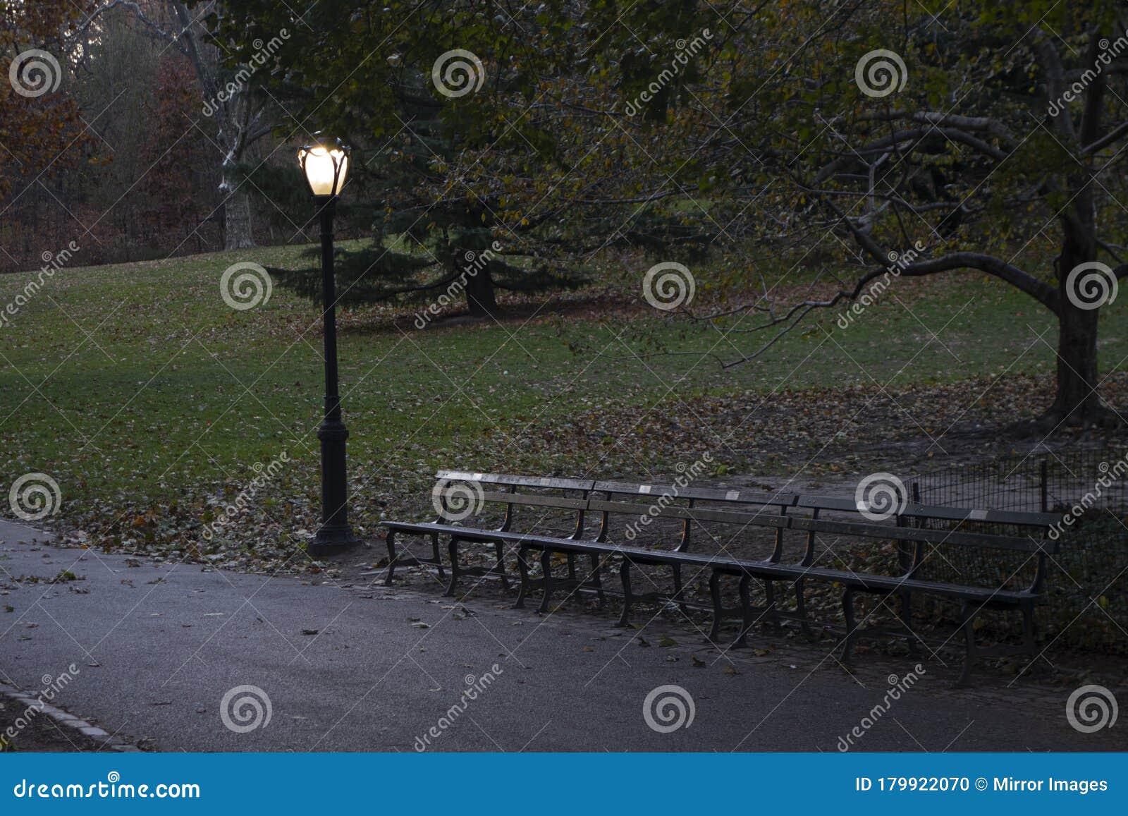 late autumn evening at the park with night light and park benches