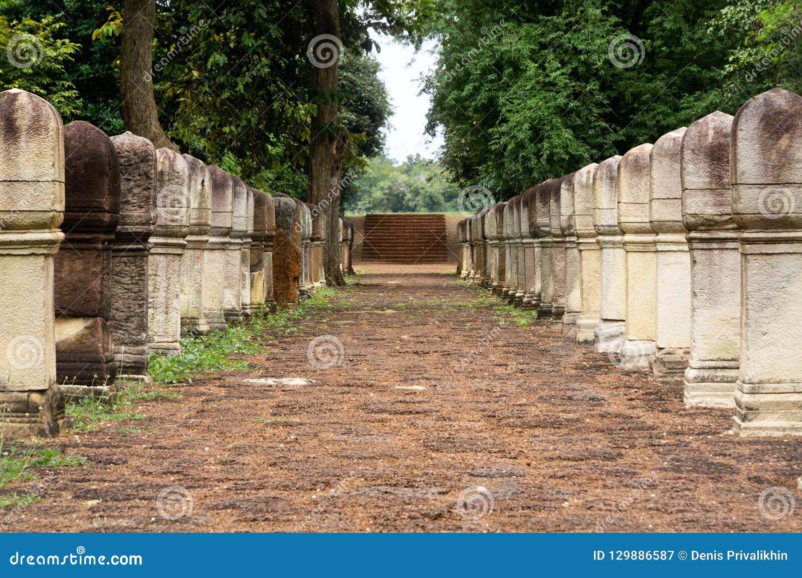 laterite stone paved walkway with free-standing stone posts to the gates of ancient khmer temple built of red sandstone and lateri